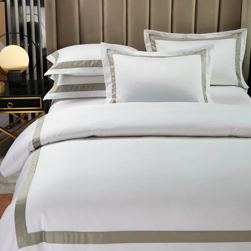 White bedding set with gray trim on a bed in a bedroom setting.