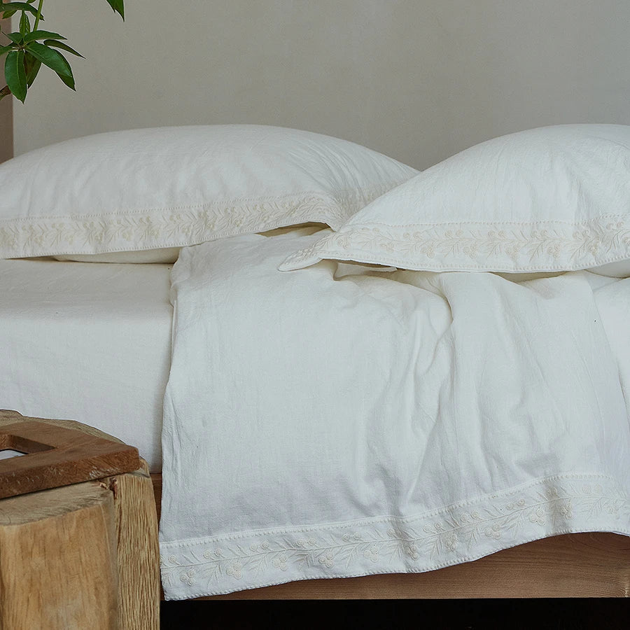 White bedding set with lace trim on a bed.