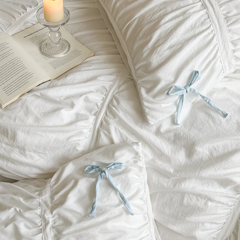 White bedding with blue ribbons and a candle on a nightstand