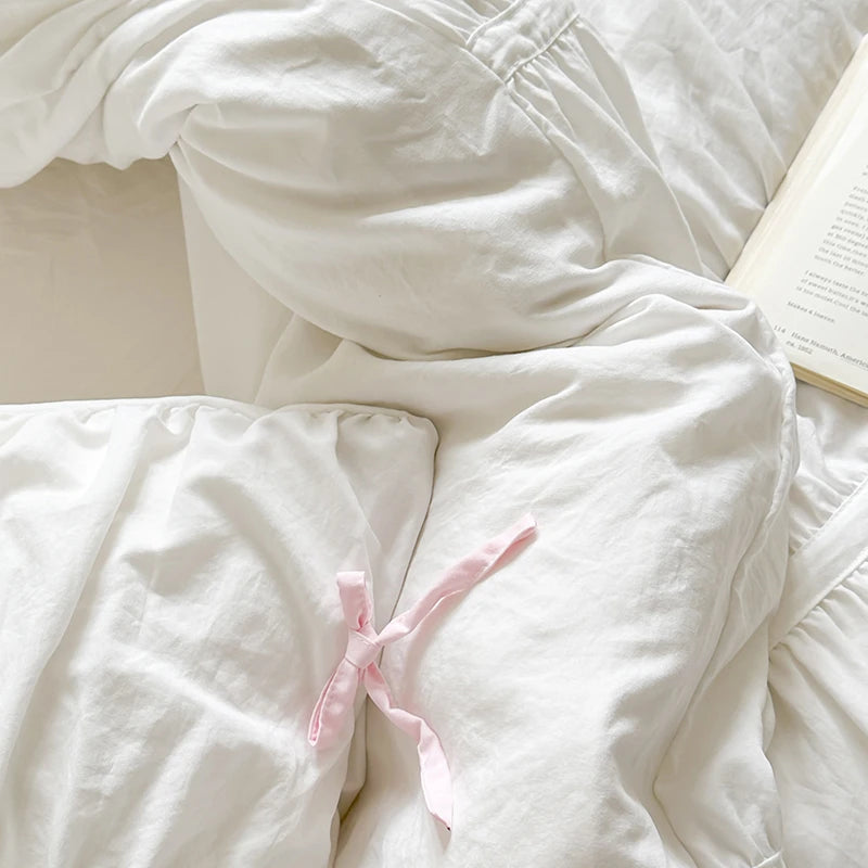White comforter with pink bow on a bed
