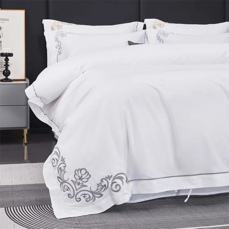White embroidered bedding set on a bed with a dark headboard.