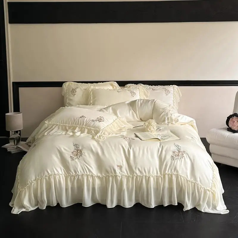 White embroidered bedding set on a bed with a dark headboard and floor.