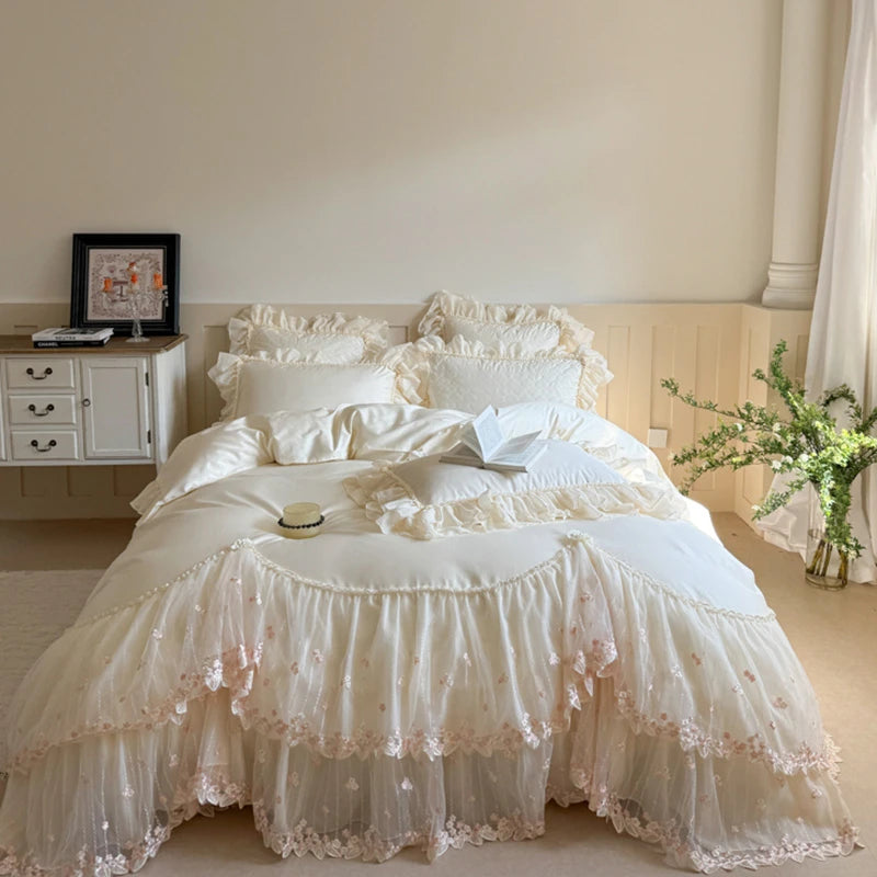 White lace bedspread on a bed in a bedroom setting with a side table and plant.