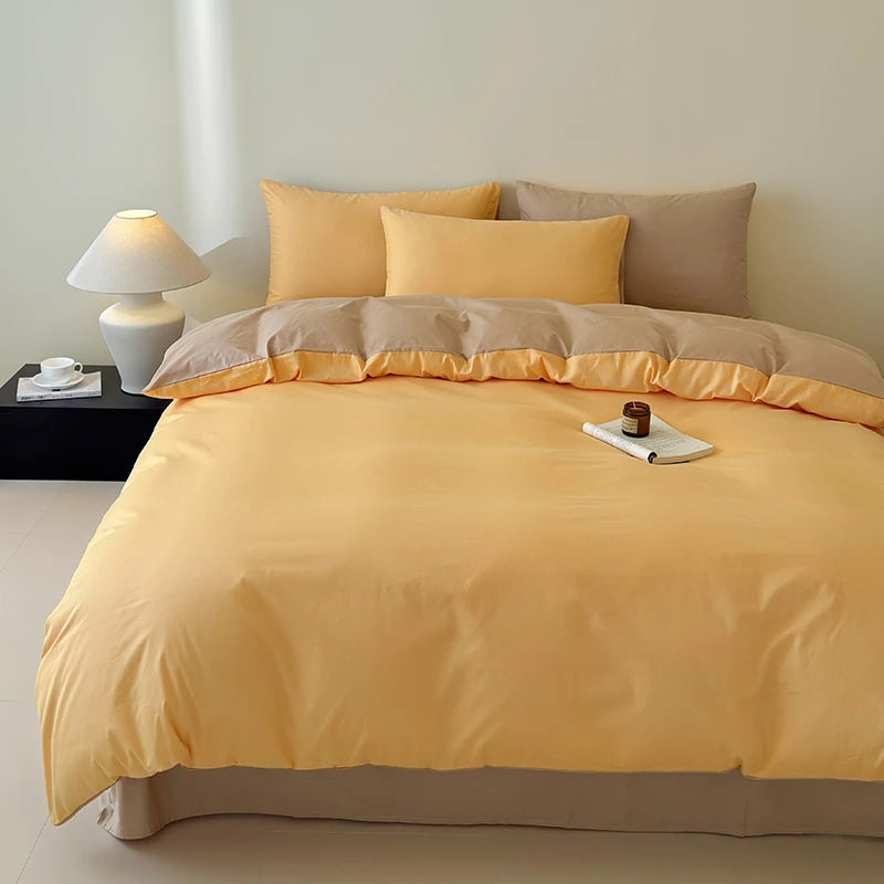 Yellow and beige bedding set on a bed with a lamp and tray in the background.